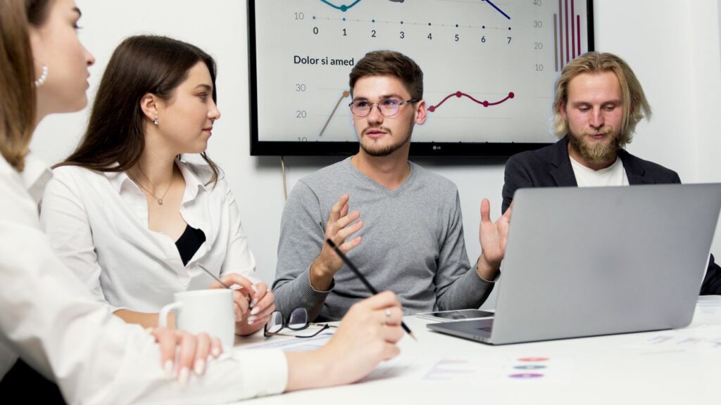 Group of colleagues discussing strategy with charts in the background.